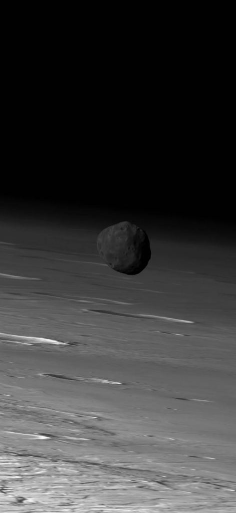 This is the original image from the High Resolution Stereo Camera (HRSC) on ESA's Mars Express spacecraft.  It captured Phobos on the Martian limb on March 26, 2010. The motion of Mars in the background is a byproduct of HRSC's line scan operation.  Image credit: ESA / DLR / FU Berlin (G. Neukum)